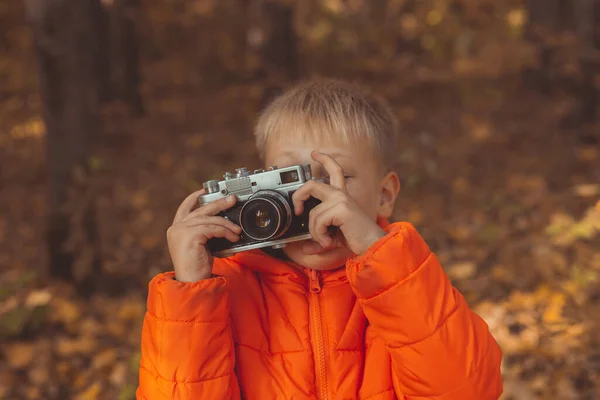 Garçon avec caméra rétro prenant des photos en plein air dans la nature d'automne. Loisirs et photographes concept — Photo