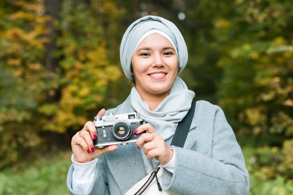 Türban takan genç bir Arap kadın parkta akıllı bir telefonla fotoğraf çekiyor. Modern Müslüman kız. — Stok fotoğraf