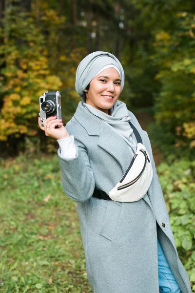 Mladá Arabka s hidžábskou šálou na hlavě fotografující s chytrým telefonem v parku. Moderní muslimská dívka — Stock fotografie