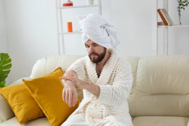 Sakallı adam ellerine el kremi sürer. Erkek konsepti için kaplıca, vücut ve cilt bakımı