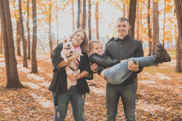 La famiglia passa il tempo in parco di autunno con un cane. Padre, madre e figlia e Jack Russell terrier cane divertirsi in autunno — Foto Stock