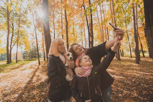 Madre, abuela y nieta pequeña con gato russell terrier perro tomando selfie por teléfono inteligente al aire libre en la naturaleza de otoño. Familia, mascotas y concepto de generación —  Fotos de Stock