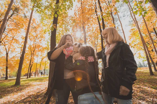 Madre y abuela e hija sostiene jack russell terrier y juega con él en otoño afuera. Concepto de mascotas y familia —  Fotos de Stock