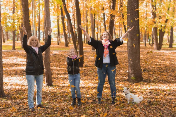 Avó e mãe com neta vomitar folhas de outono no parque de outono e se divertindo. Conceito de geração, lazer e família. — Fotografia de Stock