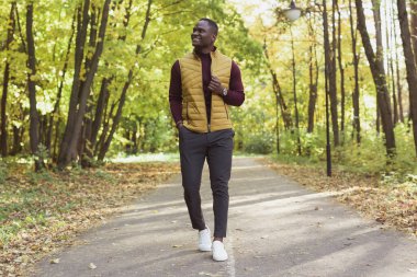 Sonbahar parkında yürüyen Afrikalı Amerikalı hippi.