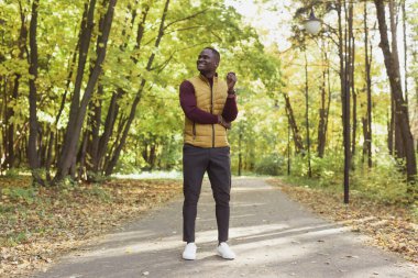 Afrikalı Amerikalı öğrenci sonbahar sezonunda parkta yürüyor.