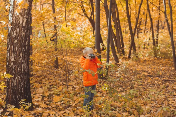 Niño con cámara retro tomando fotos al aire libre en la naturaleza de otoño. Concepto de ocio y fotógrafos —  Fotos de Stock