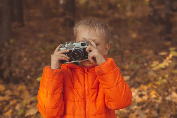 Niño con cámara retro tomando fotos al aire libre en la naturaleza de otoño. Concepto de ocio y fotógrafos —  Fotos de Stock