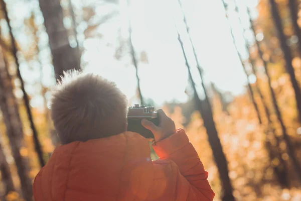 男孩带着复古相机在秋天的大自然中拍摄户外照片。休闲和摄影师概念 — 图库照片