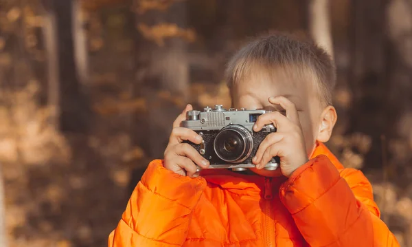 Menino com câmera retro tirando fotos ao ar livre na natureza outono. Conceito de lazer e fotógrafos — Fotografia de Stock