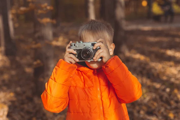 Niño con cámara retro tomando fotos al aire libre en la naturaleza de otoño. Concepto de ocio y fotógrafos — Foto de Stock