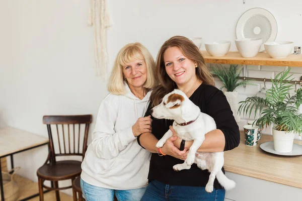 Femme âgée avec fille adulte relaxant à la maison. Femme tient son chien Jack Russell Terrier. Concept de famille — Photo