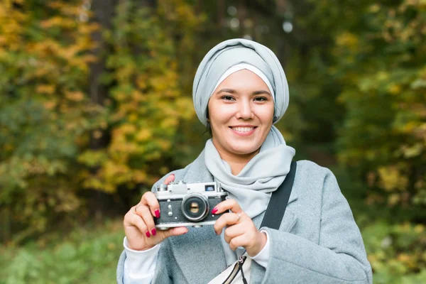 Türban takan genç bir Arap kadın parkta akıllı bir telefonla fotoğraf çekiyor. Modern Müslüman kız. — Stok fotoğraf