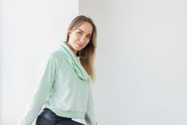 Naneli kapüşonlu güzel bir kadının portresi. Pencerenin yanında duruyor. Oturma odasında dinleniyor. Reklam için alanı ve alanı kopyala
