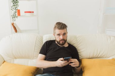 Evde cep telefonu kullanan yakışıklı bir hippi. İletişim eğlence ve teknoloji kavramı