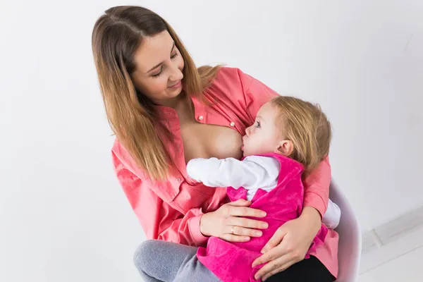 Conceito de lactação e maternidade - Jovem bela mãe segurando o bebê amamentando sentado na cadeira. — Fotografia de Stock