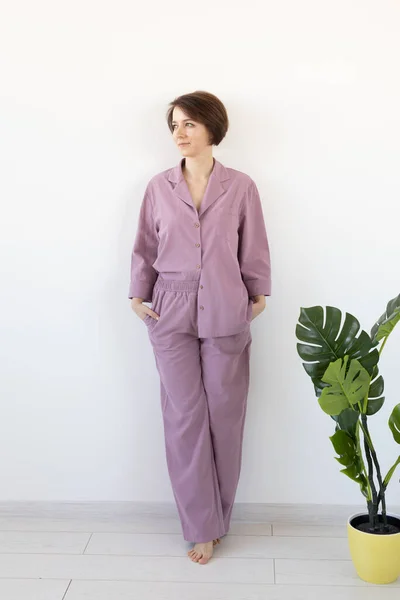 Jovem mulher atraente vestida em belo pijama colorido posando como um modelo em sua sala de estar. Confortável sleepwear, relaxamento em casa e conceito de moda feminina . — Fotografia de Stock