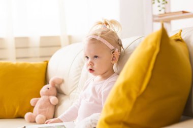 Koklear implantı olan çocuk evdeki kanepede oturuyor. Sağırlık ve tıbbi teknoloji kavramı.