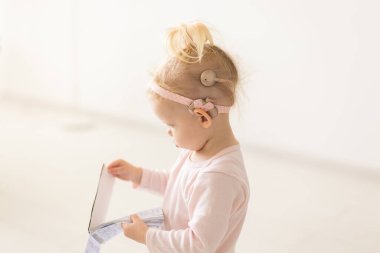 Koklear implantı olan bebek evde eğleniyor. Sağırlık ve tıbbi teknoloji kavramı.