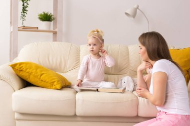 Koklear implantı olan çocuk evde annesiyle eğleniyor. Sağırlık ve tıbbi teknoloji kavramı.