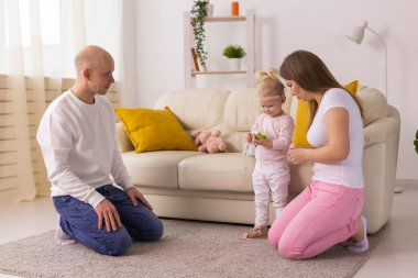 Koklear implantı olan çocuk evde anne ve babasıyla eğleniyor. Sağırlık ve tıbbi teknoloji kavramı.