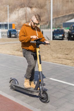 Şehirde elektrikli scooter kullandıktan sonra akıllı telefon kullanan bir adam. Yenilikçi ulaşım