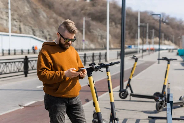 Guy betaalt voor elektrische scooter door web betaling met zijn mobiele telefoon. Modern stedelijk vervoersconcept — Stockfoto