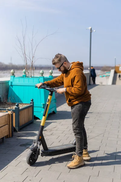 Jongeman paardrijden elektrische scooter in stedelijke achtergrond. Modern concept van vervoer en levensstijl. — Stockfoto