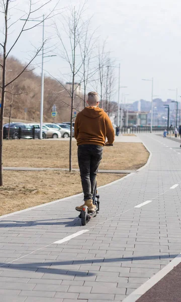 Jeune homme en scooter électrique en arrière-plan urbain. Concept moderne de transport et de mode de vie. — Photo