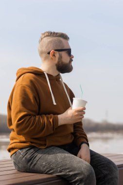 Havalı yakışıklı hippi adam elinde kokteyl tutuyor, bahar zamanı.