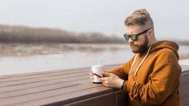 Genç hippi sokakta akıllı telefon kullanıyor. Banner sosyal medya iletişimi. Reklam için yer ve yeri kopyala
