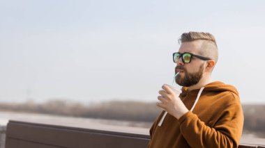 İlkbahar zamanı elinde kokteyl tutan şık, yakışıklı bir hippi. Reklam alanı ve yeri olan pankart