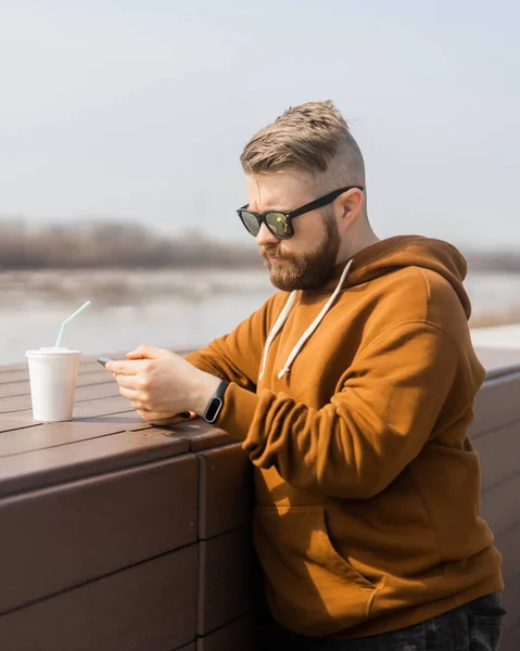 Een jonge hipster die op straat een smartphone gebruikt. Communicatie met sociale media — Stockfoto