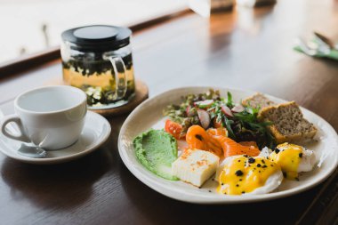 Hafif ve sağlıklı kahvaltı, çırpılmış yumurtalarla brunch tahıllı ekmek ve füme somon ve guacamole. Arugula ve turp karışımıyla servis edilir.