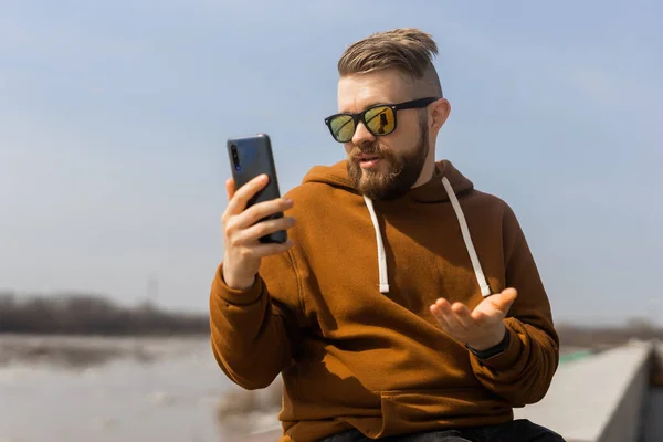 Comunicación en redes sociales. Hombre videollamada usando móvil teléfono inteligente primavera al aire libre — Foto de Stock