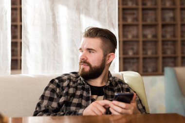 Modern dijital akıllı telefon cihazını tutan ve sosyal ağlarda sohbet eden adam. Kafedeki masada oturan adam cep telefonundan mesaj yolluyor.