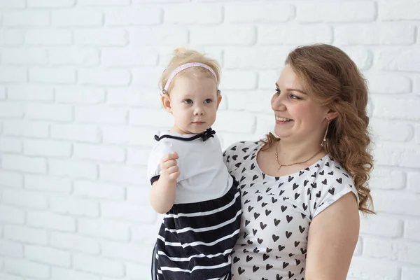 Moeder houdt haar kind met gehoorapparaten en cochleaire implantaten op witte bakstenen muur met kopieerruimte en plaats voor reclame. Concept doven en gezondheid — Stockfoto