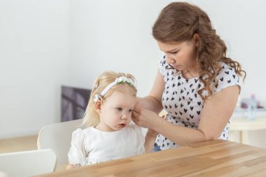 Anne, sağır küçük kızı için koklear implant takmasına yardım ediyor. İşitme cihazı ve sağırlık kavramı