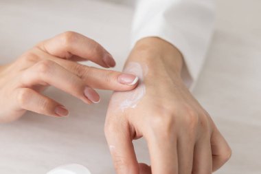Kremalı kadın elleri. Kadın ellerine krem sürüyor. Avuç içleri pürüzsüz, derileri pürüzsüz, tırnakları doğal..
