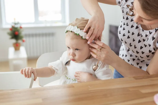 Mother helps to put on cochlear implant for her deaf little daughter. Hearing aid and deafness concept — Stock Photo, Image