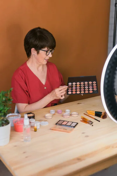 Woman holding makeup brush and blush and eyeshadow palette - beauty and cosmetics concept