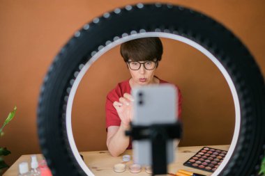 Beauty and cosmetics e-commerce and blogging concept - professional mature female make up artist testing new cosmetics recording video review on cosmetic products at home