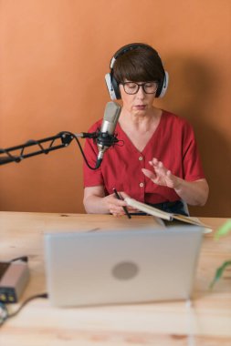 Middle-aged woman radio host making podcast recording for online show - broadcast and dj concept