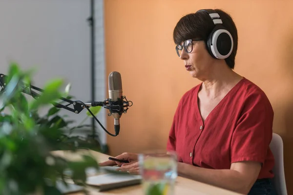 Middle-aged woman radio host making podcast recording for online show - broadcast and dj concept — Stock fotografie