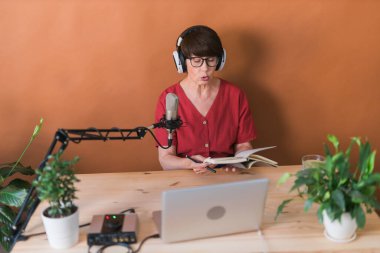 Middle-aged woman radio host making podcast recording for online show - broadcast and dj concept
