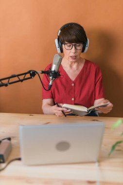 Middle-aged woman radio host making podcast recording for online show - broadcast and dj concept