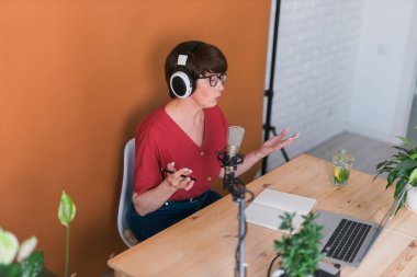 Middle-aged woman radio host making podcast recording for online show - broadcast and dj concept