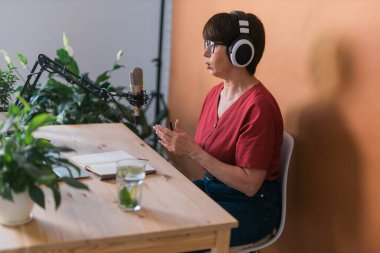 Middle-aged woman radio host making podcast recording for online show - broadcast and dj concept