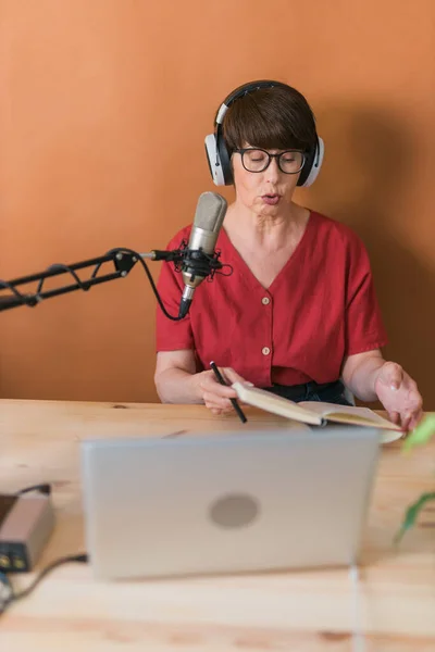 Middle-aged woman radio host making podcast recording for online show - broadcast and dj concept — Stockfoto