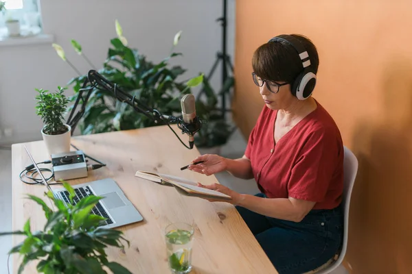 Middle-aged female radio presenter talking into the microphone and reading news - radio broadcast online concept